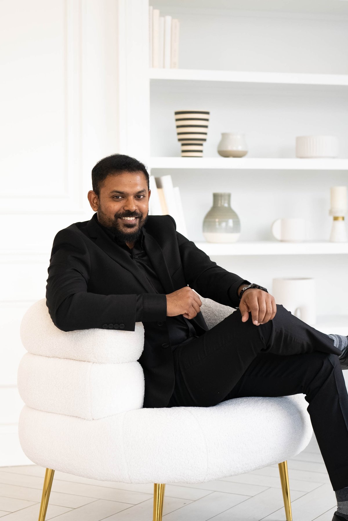 Praveen Raj, Realtor, seated in a black suit